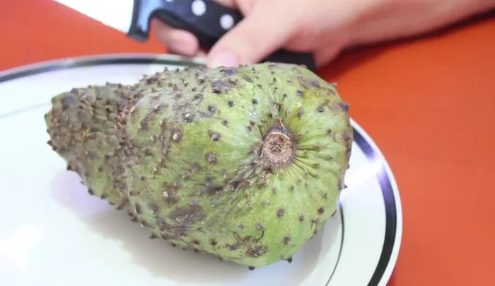 Cut the soursop in half, then into quarters. Remove the seeds and middle part.