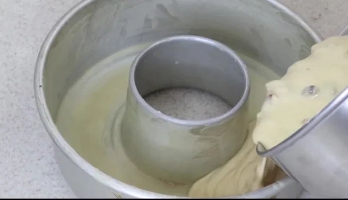 Pour the batter into the prepared mold and sprinkle with extra walnut halves on top.