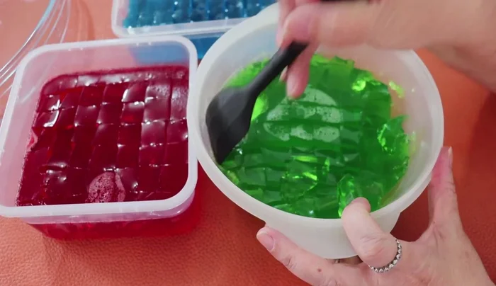 Assemble the cups: Cut the set gelatins into small squares. Layer the different colored gelatins in the disposable cups, alternating colors. Finish with a layer of milk gelatin.