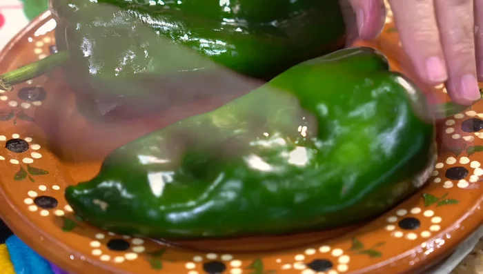 Roast the poblano chilies (lightly oiled) on a hot griddle or fire, turning until charred. Sweat them in a plastic bag to make peeling easier.