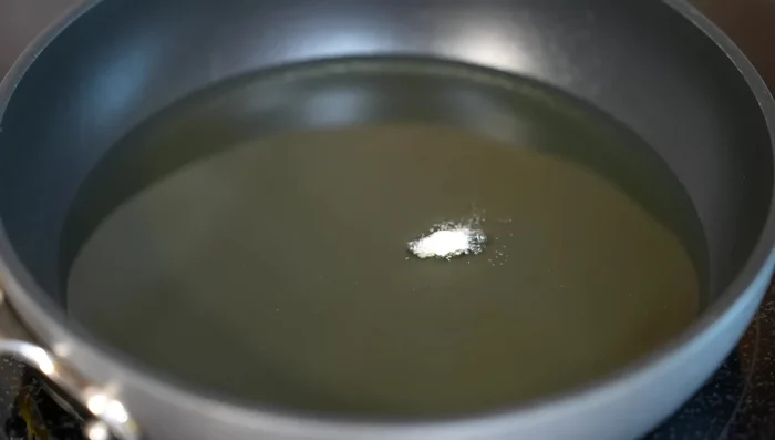 Heat oil in a pan. Test the temperature by adding a drop of the mixture; it should bubble and rise to the surface. (135.06)