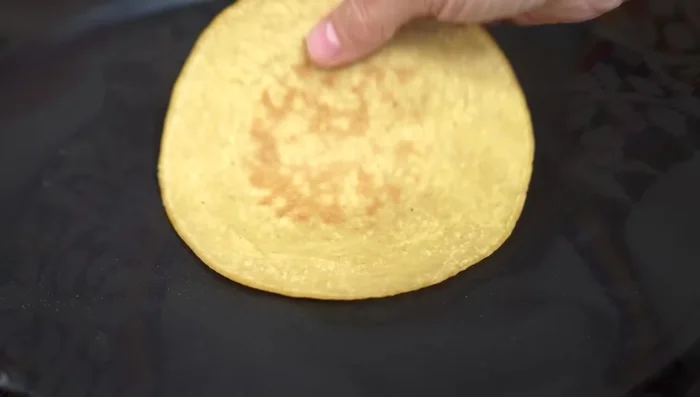 Warm corn tortillas. Add grated cheese to one side of the tortilla.