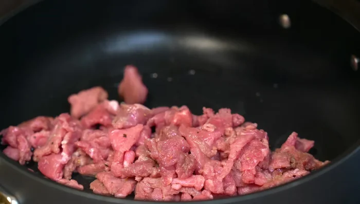 In a hot pot, sear the marinated beef over high heat. Add chopped garlic.