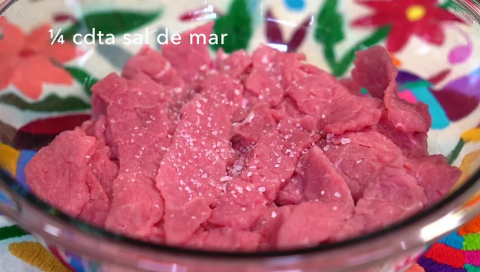 Cut the beef into strips and marinate for at least 30 minutes with salt, pepper, vinegar, and soy sauce. Add finely chopped garlic and half a small onion for extra flavor.
