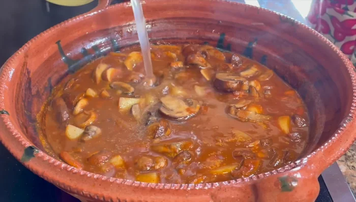 Add hot water or chicken broth, ensuring it doesn't lower the temperature of the pot. Add epazote.