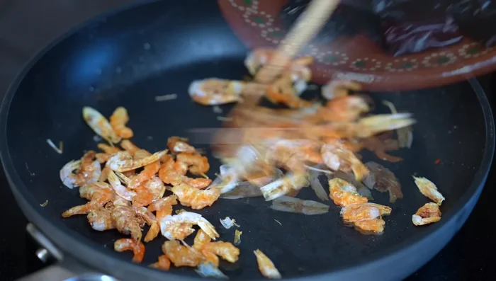 Add guajillo, ancho chilies (cut into pieces), and chiles de árbol. Stir constantly to prevent burning.