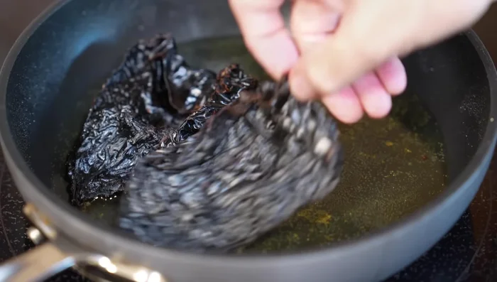 Briefly fry ancho chiles.
