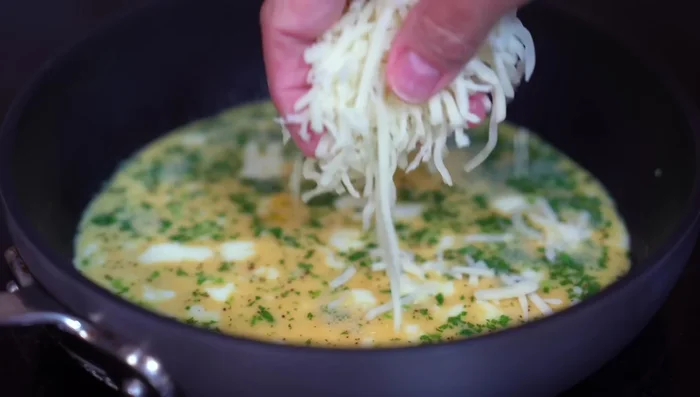 Add grated cheese to the egg's surface, and then add the filling to one half of the egg.