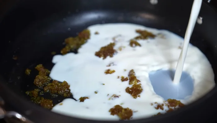 Add cold milk to the pan to lower the temperature. Stir in cream, Parmesan cheese, and the cooked bacon. Season with salt if needed.