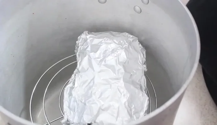 Place the foil-wrapped pork shanks in a steamer with water and steam for 2-3 hours, checking water levels to prevent drying out.