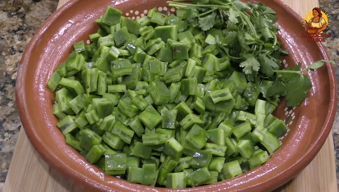 Cut nopales into pieces and clean them. Cook nopales in a pot with half a teaspoon of salt and some cilantro sprigs for 15 minutes. Let cool, then drain and remove onion and cilantro.