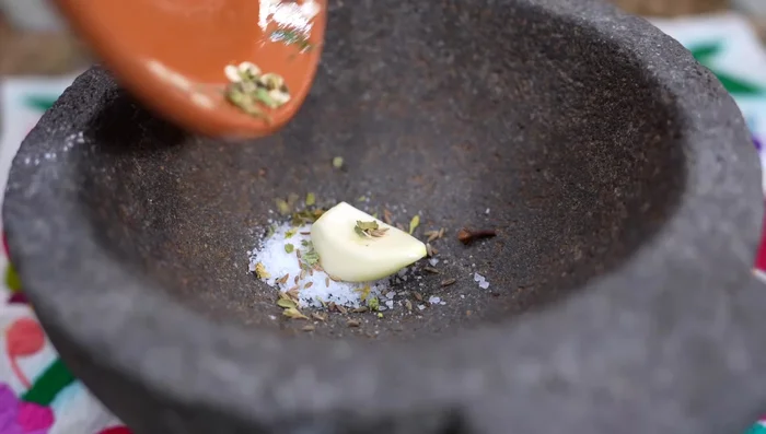 In a molcajete (or bowl), combine salt, garlic, cumin, and oregano. (Optional: Make a paste using a molcajete)
