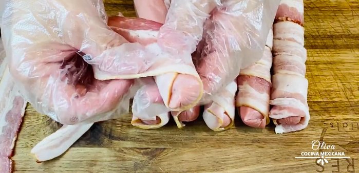 Wrap each sausage with a bacon strip, ensuring it's tightly rolled to prevent it from falling apart during cooking.