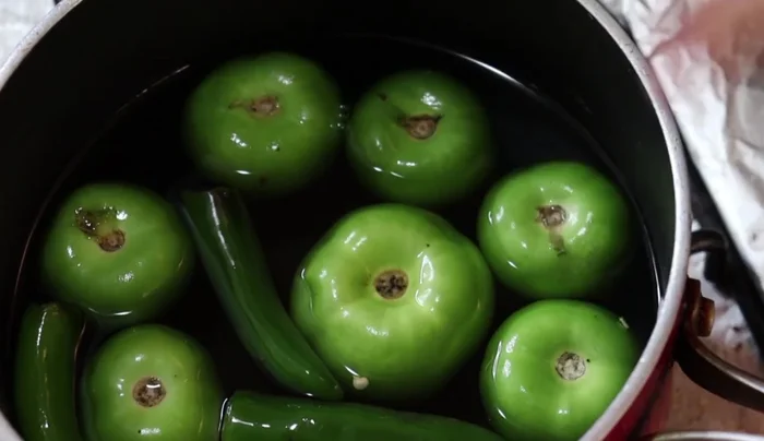 In a pot, boil 0.5 kg tomatillos and 3 green chilies.