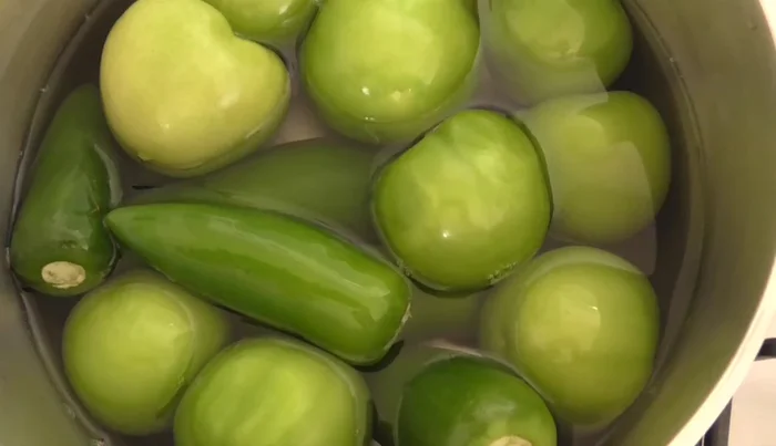 In a separate pot, boil green tomatoes and chilies until they change color.