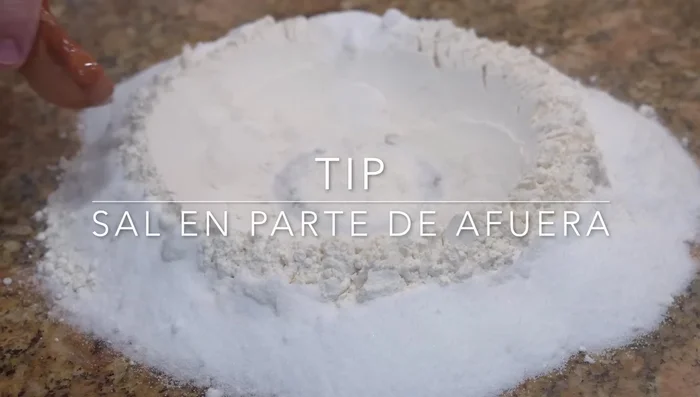 Make a flour volcano. Arrange the salt outside the volcano, the sponge in the center.
