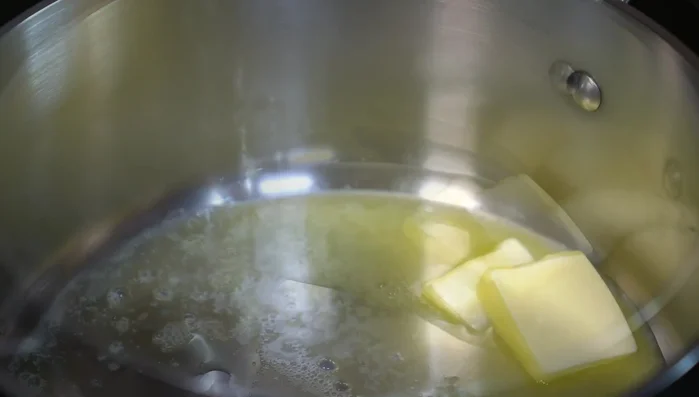 Melt butter with a splash of olive oil in a pan. Add grated onion and pressed garlic; cook until golden.