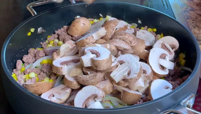 Add sliced mushrooms, season with salt, and stir.