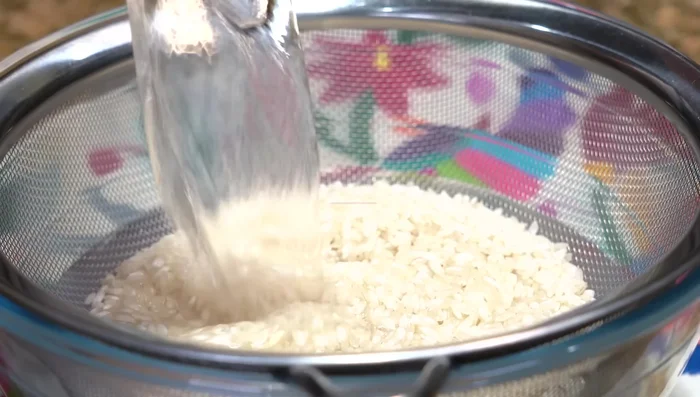 Rinse the rice to remove excess starch. Soak in hot (not boiling) water, stir with clean hands, and rinse with cold water. Drain.