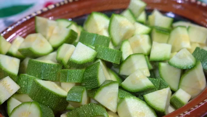 Prepare the zucchini by removing ends and cutting into cubes. Chop the onion, garlic, and leek.