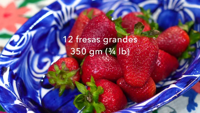 Wash and remove stems from strawberries. Chop three strawberries for garnish, blend the rest.