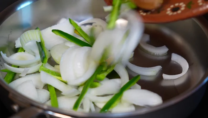 Sauté onions and chilies: In a hot pan with oil, sauté sliced onions and serrano chilies until slightly softened. Add salt.