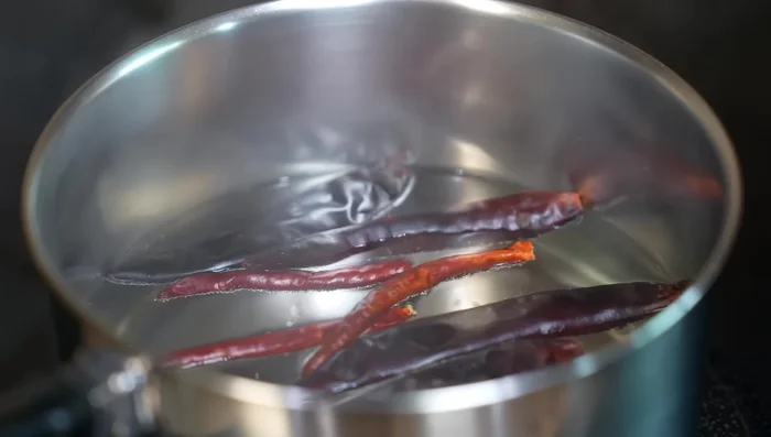 Prepare the sauce: In hot water, add guajillo and árbol chilies. After 5 minutes, add tomatoes and green tomatoes. Once the green tomatoes change color and the tomato skins burst, remove from heat and let cool.