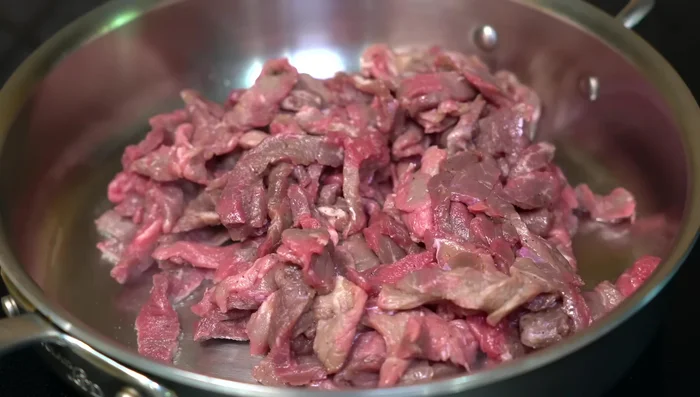 In hot oil, fry the seasoned beef over high heat. Add chopped garlic. After 7-8 minutes (when sealed), lower heat and cover until the meat releases its juices.