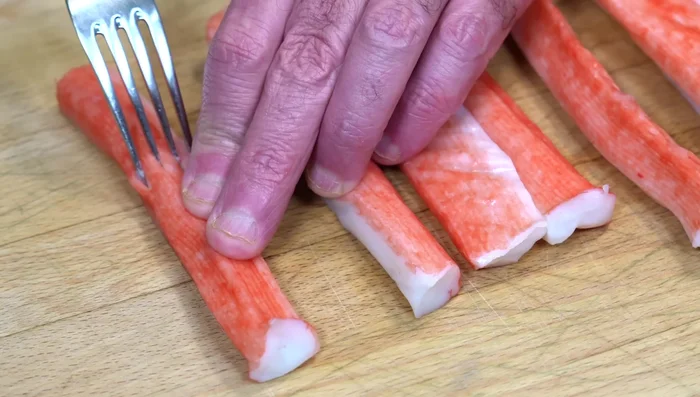 Shred the surimi using a fork. Divide the surimi into two portions and shred each half.