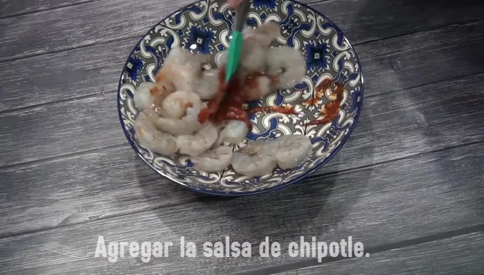 In a bowl, combine the cleaned shrimp with chipotle peppers in adobo sauce, salt, and ground pepper. Mix well to marinate.