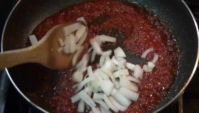 Add the chopped onion and half of the chopped serrano pepper to the pan with the chorizo. (Start adding at 138.35)